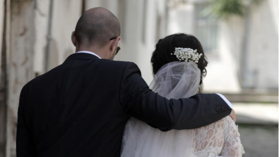 Ein Hochzeitsgast legt tröstend den Arm um die Braut