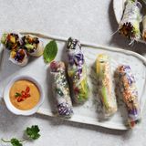 Sommerrollen      Zutaten: 50 g Glasnudeln, 80 g Rotkohl, je ⅓ grüne, rote und gelbe Paprika, 1 große Karotte (ca. 100 g), 1 kleine Avocado, 1 TL frisch gepresster Limettensaft, ½ Bund Koriandergrün, 3 Stängel Minze, 16 kleine Reispapierblätter (Ø 16 cm), 2–3 EL gerösteter Sesam      Zubereitung: Die Glasnudeln nach Packungsanleitung zubereiten und in mundgerechte Stücke schneiden. Den Rotkohl und die Paprika putzen und in feine Streifen schneiden. Die Karotte schälen und ebenfalls in feine Streifen schneiden. Die Avocado halbieren, entsteinen, das Fruchtfleisch aus den Schalen lösen und in feine Scheiben schneiden, dann mit dem Limettensaft beträufeln. Den Koriander und die Minze waschen und die Blättchen grob hacken. Je drei bis vier Reispapierblätter nacheinander kurz in eine flache Schale mit lauwarmem Wasser tauchen und nebeneinander mit der glatten Seite nach unten auf die Arbeitsfläche legen. Jedes Blatt mit Sesam bestreuen. Gemüse, Kräuter und Glasnudeln als Füllung mittig im unteren Drittel der Blätter platzieren, die Seiten umklappen und die Blätter von unten nach oben mit ein wenig Druck aufrollen.