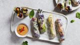 Sommerrollen      Zutaten: 50 g Glasnudeln, 80 g Rotkohl, je ⅓ grüne, rote und gelbe Paprika, 1 große Karotte (ca. 100 g), 1 kleine Avocado, 1 TL frisch gepresster Limettensaft, ½ Bund Koriandergrün, 3 Stängel Minze, 16 kleine Reispapierblätter (Ø 16 cm), 2–3 EL gerösteter Sesam      Zubereitung: Die Glasnudeln nach Packungsanleitung zubereiten und in mundgerechte Stücke schneiden. Den Rotkohl und die Paprika putzen und in feine Streifen schneiden. Die Karotte schälen und ebenfalls in feine Streifen schneiden. Die Avocado halbieren, entsteinen, das Fruchtfleisch aus den Schalen lösen und in feine Scheiben schneiden, dann mit dem Limettensaft beträufeln. Den Koriander und die Minze waschen und die Blättchen grob hacken. Je drei bis vier Reispapierblätter nacheinander kurz in eine flache Schale mit lauwarmem Wasser tauchen und nebeneinander mit der glatten Seite nach unten auf die Arbeitsfläche legen. Jedes Blatt mit Sesam bestreuen. Gemüse, Kräuter und Glasnudeln als Füllung mittig im unteren Drittel der Blätter platzieren, die Seiten umklappen und die Blätter von unten nach oben mit ein wenig Druck aufrollen.