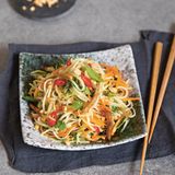 Vietnamesischer grüner Papayasalat      Zutaten:  Papayasalat: ½ grüne Papaya (ca. 200 g), 1 große Karotte (ca. 100 g), 1 Handvoll vietnamesische Kräuter (z.B. Koriandergrün, Minze, Thaibasilikum), 3 EL geröstete Erdnusskerne, 1 Portion klassische Dip-Sauce, 2 TL geröstetes Sesamöl, 100 g Naturtofu, 1 EL Bratöl (z.B. Sojaöl), 1–2 EL Sojasauce  Klassische Dip-Sauce: 10 g Zucker, 2 EL »No-Fish-Sauce« alternativ Sojasauce, 2 EL frisch gepresster Limettensaft, ½–1 kleine rote Chilischote, 1 Knoblauchzehe  Außerdem: 1 Handvoll vietnamesische Kräuter 2 EL Röstschalotten      Zubereitung: Die Papaya und die Karotte schälen und mit einem Julienneschneider in feine Streifen schneiden. Die Kräuter waschen und Blättchen grob hacken. Die Erdnüsse mittelfein hacken. Die Gemüsestreifen mit den Kräutern und 2 EL Erdnüssen in eine Salatschüssel geben und leicht durchkneten. Die Dip-Sauce (Für die klassische Dip-Sauce den Zucker in einem Schälchen mit 30 ml heißem Wasser übergießen und unter Rühren auflösen. Mit der »No-Fish-Sauce« und dem Limettensaft verrühren. Die Chilischote putzen, auf Wunsch entkernen, fein würfeln und zugeben. Den Knoblauch abziehen, fein würfeln und ebenfalls zugeben. Die Sauce mindestens 15 Minuten ziehen lassen – am besten schmeckt sie, wenn sie über Nacht im Kühlschrank durchzieht.) mit dem Sesamöl vermischen, als Dressing unter den Salat heben und diesen mindestens 15 Minuten ziehen lassen. Inzwischen den Tofu in feine Streifen schneiden. Das Bratöl in einer mittelgroßen Pfanne erhitzen. Den Tofu darin unter gelegentlichem Rühren bei mittlerer Temperatur in etwa 7–10 Minuten goldbraun braten. Die Sojasauce zugeben und unter Rühren einkochen lassen. Den Salat nochmal durchmischen und auf zwei Tellern anrichten. Mit Tofustreifen, übrigen Erdnüssen, Kräutern und Röstschalotten garniert servieren.