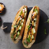 Vietnamesisches Sandwich mit Pilz-Pâté und Tofu      Zutaten: 1 großes Baguette, 200 g Austernpilze, 1 kleine Zwiebel, 2 EL Bratöl (z.B. Sojaöl), 1 Knoblauchzehe, 4 EL Sojasauce, 30 g Cashewkerne, 1 EL frisch gepresster Limettensaft, frisch gemahlener weißer Pfeffer, 1 TL geröstetes Sesamöl, 200 g Naturtofu, 1 Handvoll vietnamesische Kräuter (z.B. Perilla und Minze), ¼ Salatgurke, 3 EL eingelegte Karotten-Rettich-Streifen, 2 EL eingelegte Radieschen      Zubereitung: Das Baguette im Ofen bei 180°C Ober- und Unterhitze knusprig aufbacken. Die Austernpilze putzen und in Streifen zupfen. Die Zwiebel abziehen und grob würfeln. 1 EL Öl in einem Wok oder einer Pfanne erhitzen. Die Pilze und die Zwiebel darin bei mittlerer bis hoher Temperatur in 7–10 Minuten goldbraun anbraten. Den Knoblauch abziehen, fein würfeln, zugeben und 1 Minute mitbraten. Alles mit 2 EL Sojasauce ablöschen und einkochen lassen. Die Pilzmischung in ein hohes Gefäß geben und mit den Cashewkernen fein pürieren. Mit 1 EL Sojasauce, Limettensaft, Pfeffer und Sesamöl abschmecken. Den Tofu in acht gleich große Stücke schneiden. Das übrige Bratöl (1 EL) in einer Pfanne erhitzen und den Tofu darin von beiden Seiten bei mittlerer Temperatur 7–10 Minuten anbraten. Mit der übrigen Sojasauce (1 EL) ablöschen, diese einkochen lassen und den Tofu auf Küchenpapier abtropfen lassen. Die Kräuter waschen und die Blättchen abzupfen. Die Gurke waschen und mit einem Sparschäler in feinen Streifen abziehen. Das Baguette quer halbieren und die Hälften längs fast ganz durchschneiden. Die unteren und oberen Hälften gleichmäßig mit der Pilz-Pâté bestreichen und die jeweils unteren Hälften mit Gurkenstreifen belegen. Den Tofu gleichmäßig darauf verteilen, mit eingelegtem Gemüse sowie Kräutern belegen und das Sandwich zusammengeklappt servieren.      Eingelegtes Gemüse: 2 mittelgroße Karotten (ca. 150 g), ½ Rettich (ca. 150 g), ½ TL Salz, 40 g Zucker, 100 ml heller Reisessig  Zubereitung: Die Karotten und den Rettich schälen und mit einem Julienneschneider in feine Streifen schneiden. Diese in einer Schüssel mit dem Salz vermischen und mit den Händen leicht verkneten. Etwa 15 Minuten Wasser ziehen lassen. Inzwischen den Zucker in einer Schüssel mit 150 ml kochendem Wasser übergießen und darin auflösen. Den Reisessig zugeben und die Mischung komplett abkühlen lassen. Die Karotten-RettichStreifen in einem Sieb abgießen und leicht ausdrücken, dann in ein sterilisiertes Glas geben, mit der Essig-Zucker-Mischung übergießen, verschließen und bei Raumtemperatur mindestens 1 Tag ziehen lassen. Das Gemüse ist im Kühlschrank bis zu 1 Monat haltbar. Auf dieselbe Weise lassen sich auch andere Gemüsesorten einlegen, wie in feine Scheiben geschnittene Radieschen oder Gurken.