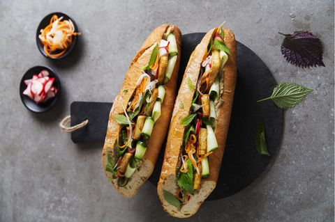 Vietnamesisches Sandwich mit Pilz-Pâté und Tofu      Zutaten: 1 großes Baguette, 200 g Austernpilze, 1 kleine Zwiebel, 2 EL Bratöl (z.B. Sojaöl), 1 Knoblauchzehe, 4 EL Sojasauce, 30 g Cashewkerne, 1 EL frisch gepresster Limettensaft, frisch gemahlener weißer Pfeffer, 1 TL geröstetes Sesamöl, 200 g Naturtofu, 1 Handvoll vietnamesische Kräuter (z.B. Perilla und Minze), ¼ Salatgurke, 3 EL eingelegte Karotten-Rettich-Streifen, 2 EL eingelegte Radieschen      Zubereitung: Das Baguette im Ofen bei 180°C Ober- und Unterhitze knusprig aufbacken. Die Austernpilze putzen und in Streifen zupfen. Die Zwiebel abziehen und grob würfeln. 1 EL Öl in einem Wok oder einer Pfanne erhitzen. Die Pilze und die Zwiebel darin bei mittlerer bis hoher Temperatur in 7–10 Minuten goldbraun anbraten. Den Knoblauch abziehen, fein würfeln, zugeben und 1 Minute mitbraten. Alles mit 2 EL Sojasauce ablöschen und einkochen lassen. Die Pilzmischung in ein hohes Gefäß geben und mit den Cashewkernen fein pürieren. Mit 1 EL Sojasauce, Limettensaft, Pfeffer und Sesamöl abschmecken. Den Tofu in acht gleich große Stücke schneiden. Das übrige Bratöl (1 EL) in einer Pfanne erhitzen und den Tofu darin von beiden Seiten bei mittlerer Temperatur 7–10 Minuten anbraten. Mit der übrigen Sojasauce (1 EL) ablöschen, diese einkochen lassen und den Tofu auf Küchenpapier abtropfen lassen. Die Kräuter waschen und die Blättchen abzupfen. Die Gurke waschen und mit einem Sparschäler in feinen Streifen abziehen. Das Baguette quer halbieren und die Hälften längs fast ganz durchschneiden. Die unteren und oberen Hälften gleichmäßig mit der Pilz-Pâté bestreichen und die jeweils unteren Hälften mit Gurkenstreifen belegen. Den Tofu gleichmäßig darauf verteilen, mit eingelegtem Gemüse sowie Kräutern belegen und das Sandwich zusammengeklappt servieren.      Eingelegtes Gemüse: 2 mittelgroße Karotten (ca. 150 g), ½ Rettich (ca. 150 g), ½ TL Salz, 40 g Zucker, 100 ml heller Reisessig  Zubereitung: Die Karotten und den Rettich schälen und mit einem Julienneschneider in feine Streifen schneiden. Diese in einer Schüssel mit dem Salz vermischen und mit den Händen leicht verkneten. Etwa 15 Minuten Wasser ziehen lassen. Inzwischen den Zucker in einer Schüssel mit 150 ml kochendem Wasser übergießen und darin auflösen. Den Reisessig zugeben und die Mischung komplett abkühlen lassen. Die Karotten-RettichStreifen in einem Sieb abgießen und leicht ausdrücken, dann in ein sterilisiertes Glas geben, mit der Essig-Zucker-Mischung übergießen, verschließen und bei Raumtemperatur mindestens 1 Tag ziehen lassen. Das Gemüse ist im Kühlschrank bis zu 1 Monat haltbar. Auf dieselbe Weise lassen sich auch andere Gemüsesorten einlegen, wie in feine Scheiben geschnittene Radieschen oder Gurken.