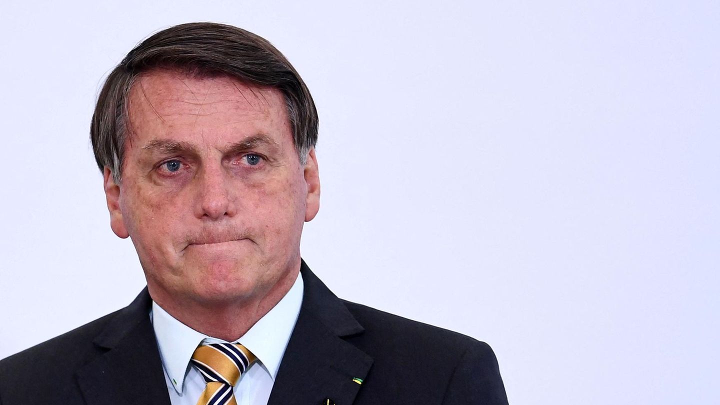 Ein älterer weißer Mann mit dunkelgrauem Seitenscheitel trägt Anzug und schaut mit verkniffenem Mund