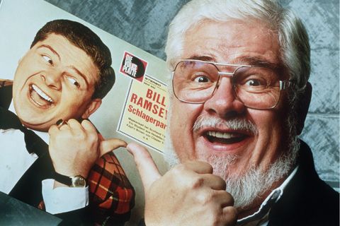 Bill Ramsey hält eine seiner alten Platten in der Hand und lacht in die Kamera