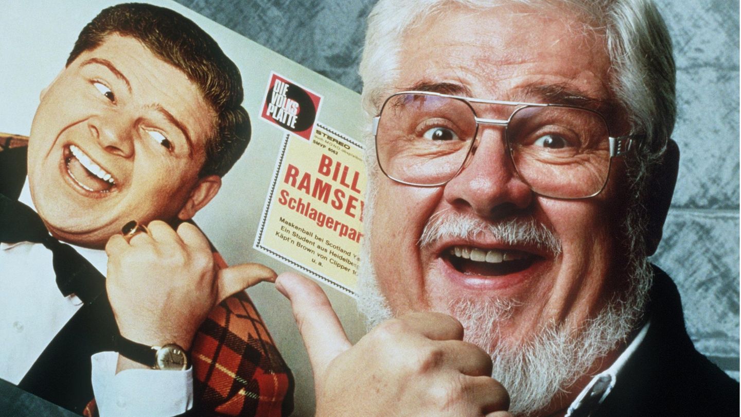 Bill Ramsey hält eine seiner alten Platten in der Hand und lacht in die Kamera