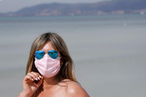 Eine Mallorca-Urlauberin trägt eine medizinische Maske, während sie die Sonne am Strand von El Arenal genießt.