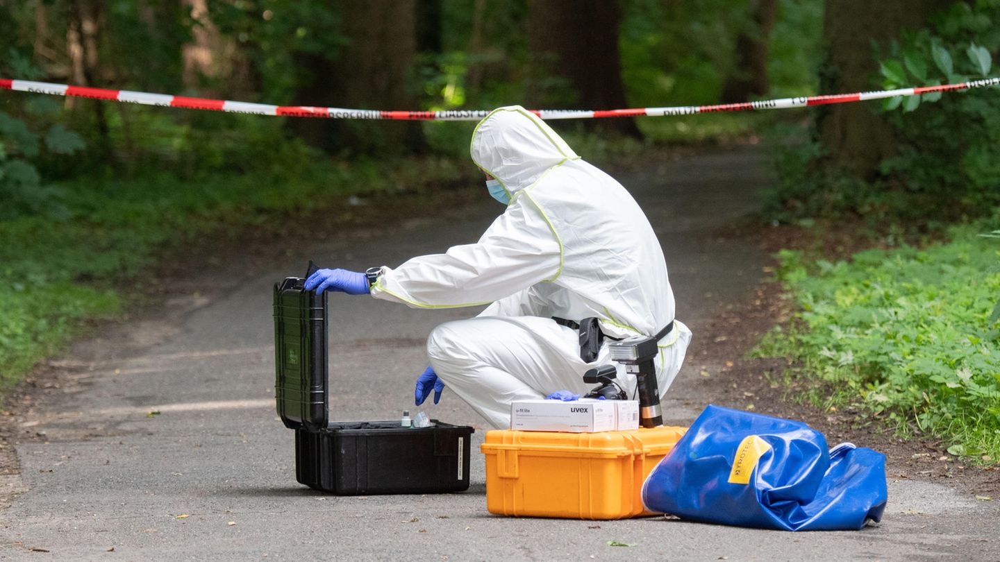 Ein Mitarbeiter der Spurensicherung trägt einen weißen Schutzanzug und nimmt Material aus einem Koffer
