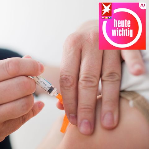 Ein Kinderarzt sticht einem Kind eine Spritze mit Impfstoff in den Oberarm