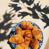 Croissants mit Joghurt      Zutaten:   Für den Teig: ½ Pck. Trockenhefe, 1 TL Zucker, 100 ml Milch, 100 g Joghurt, 100 ml Olivenöl, ½ TL Salz, 300 g Mehl  Außerdem: Mehl für die Arbeitsfläche, 2 Eigelb (M), 2 EL Sesam      Zubereitung:  Hefe, Zucker und Milch in einer großen Schüssel mit dem Schneebesen verrühren. Den Joghurt esslöffelweise einarbeiten. Das Olivenöl mit dem Salz gründlich untermischen. Das Mehl mit einem Kochlöffel unterrühren und alle Zutaten mit den Händen zu einem glatten, geschmeidigen Teig verkneten. Den Teig zu einer Kugel formen und abgedeckt bei Zimmertemperatur ca. 30 Min. ruhen lassen. Den Backofen auf 180° vorheizen, ein Backblech mit Backpapier belegen. Die Arbeitsplatte mit etwas Mehl bestäuben. Den Teig zu einem ca. 5 mm dicken Kreis ausrollen und wie einen Kuchen in 12 Stücke schneiden. Jedes Stück von der breiten Seite her zu einem kleinen Croissant aufrollen und auf das Backblech legen. Die Eigelbe verrühren und die Croissants damit bestreichen. Den Sesam darüberstreuen und die Croissants im Backofen in ca. 20 Min. goldgelb backen.