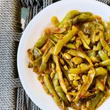 Grüne Bohnen      Zutaten:   3 Tomaten, 800 g grüne Bohnen, 1 Zwiebel, 1 Knoblauchzehe, 4 Stängel glatte Petersilie, 8 EL Olivenöl, 1 EL Tomatenmark, Salz, Pfeffer      Zubereitung:  Die Tomaten waschen und auf der Küchenreibe in eine Schüssel reiben, die Stielansätze dabei entfernen. Die Bohnen waschen und putzen. Die Zwiebel und den Knoblauch schälen und in kleine Würfel schneiden. Die Petersilie waschen und trocken schütteln, die Blätter abzupfen und fein hacken. Das Olivenöl in einem Topf erhitzen und die Zwiebelwürfel darin kurz andünsten. Knoblauch, Petersilie und Tomatenmark 2–3 Min. mitdünsten. Mit Salz und Pfeffer würzen, die Tomaten untermischen und alles weitere 3 Min. köcheln lassen. Die Bohnen zur Tomatenmischung geben und so viel Wasser angießen, dass das Gemüse gerade bedeckt ist. Die Bohnen unter gelegentlichem Rühren in ca. 40 Min. gar köcheln lassen. Falls nötig, noch etwas Wasser hinzufügen.