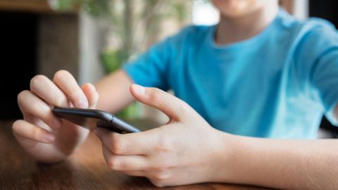 Ein Junge im Teenager-Alter hält ein Smartphone in der Hand