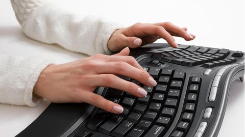 Ergonomische Tastatur: Eine Frau tippt an einer ergonomischen Tastatur.