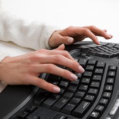 Ergonomische Tastatur: Eine Frau tippt an einer ergonomischen Tastatur.