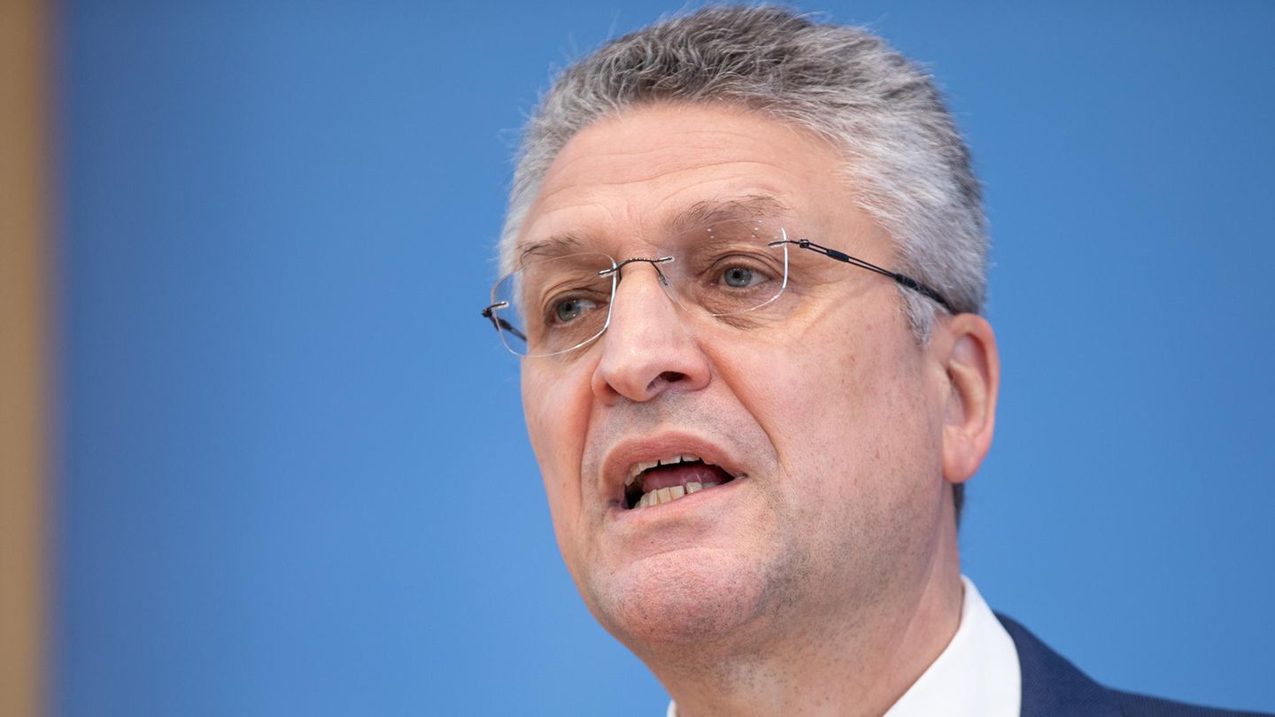 Ein graugelockter weißer Mann mit randloser Brille und Anzug spricht von einem Podium herab