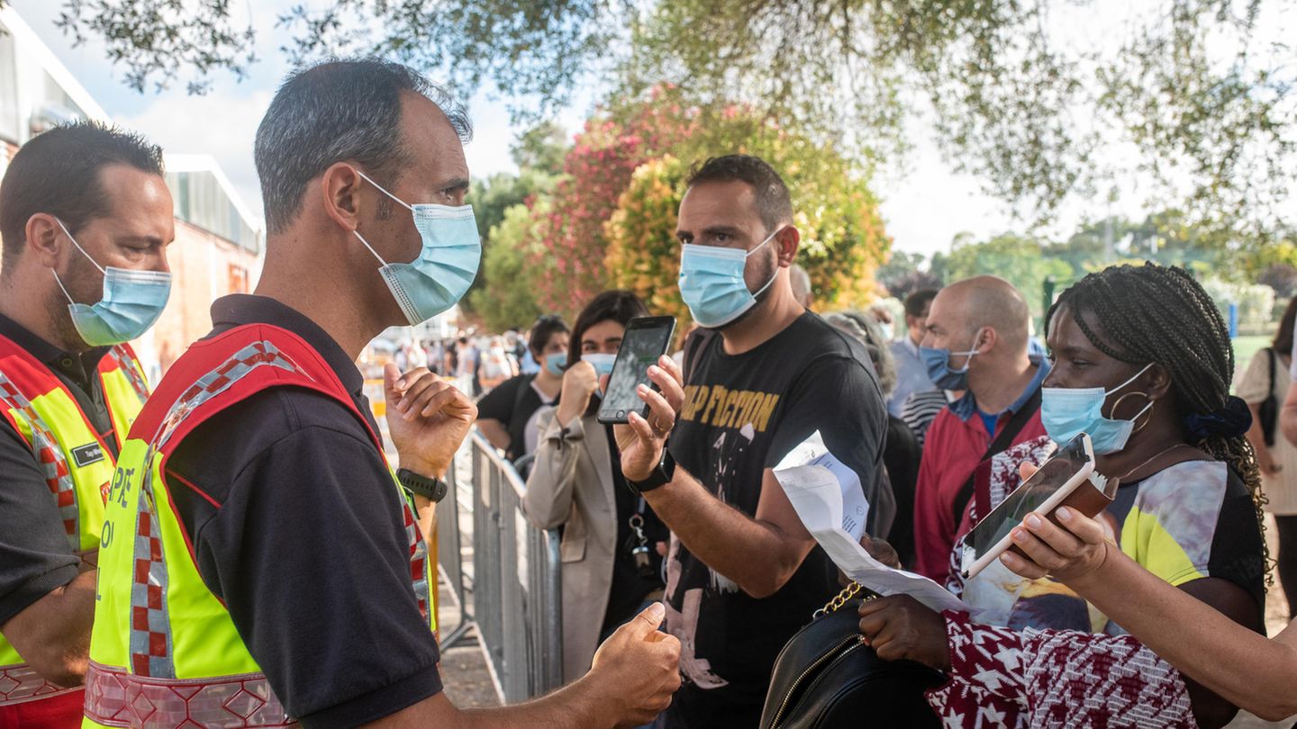 Menschen mit Mund-Nasen-Bedeckung stehen in Lissabon Schlange vor einem Corona-Impfzentrum auf dem Universitätsgelände