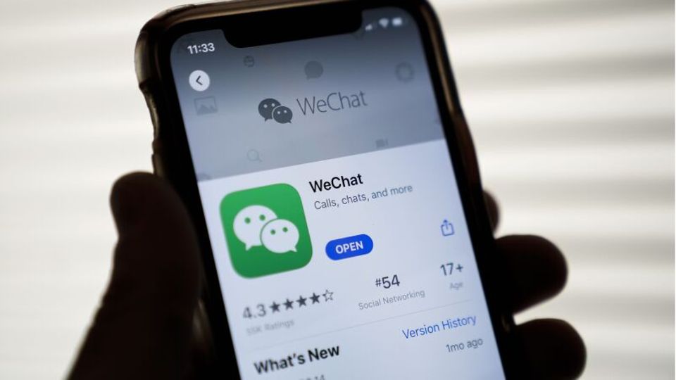 Eine Hand hält ein Smartphone, auf dem Bildschirm sieht man die App WeChat im App-Store
