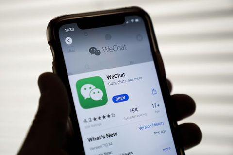 Eine Hand hält ein Smartphone, auf dem Bildschirm sieht man die App WeChat im App-Store