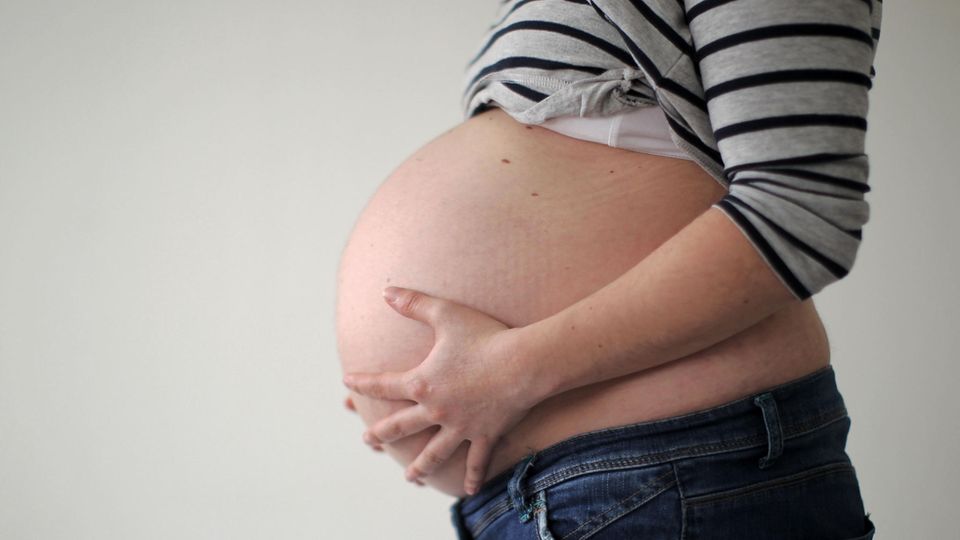 Eine hoch schwangere Frau hält ihren Bauch