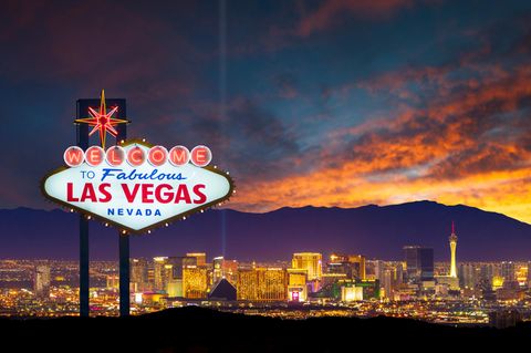 Das Las Vegas-Ortsschild mit der Skyline im Hintergrund bei Dämmerung