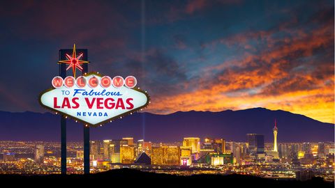 Das Las Vegas-Ortsschild mit der Skyline im Hintergrund bei Dämmerung