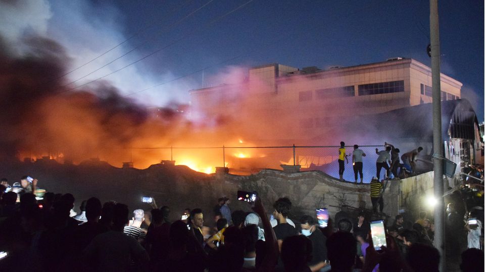 Menschen stehen in der Nacht vor einem brennenden Gebäude