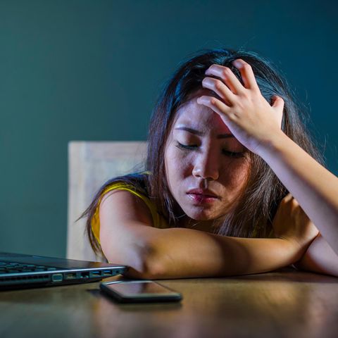 Bedrückte Frau mit Handy und Laptop