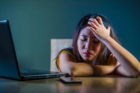 Bedrückte Frau mit Handy und Laptop