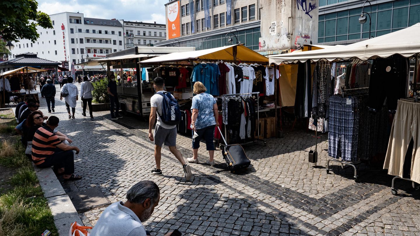 Menschen gehen an den Marktständen auf dem Hermannplatz in Neukölln vorbei