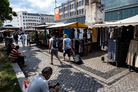 Menschen gehen an den Marktständen auf dem Hermannplatz in Neukölln vorbei