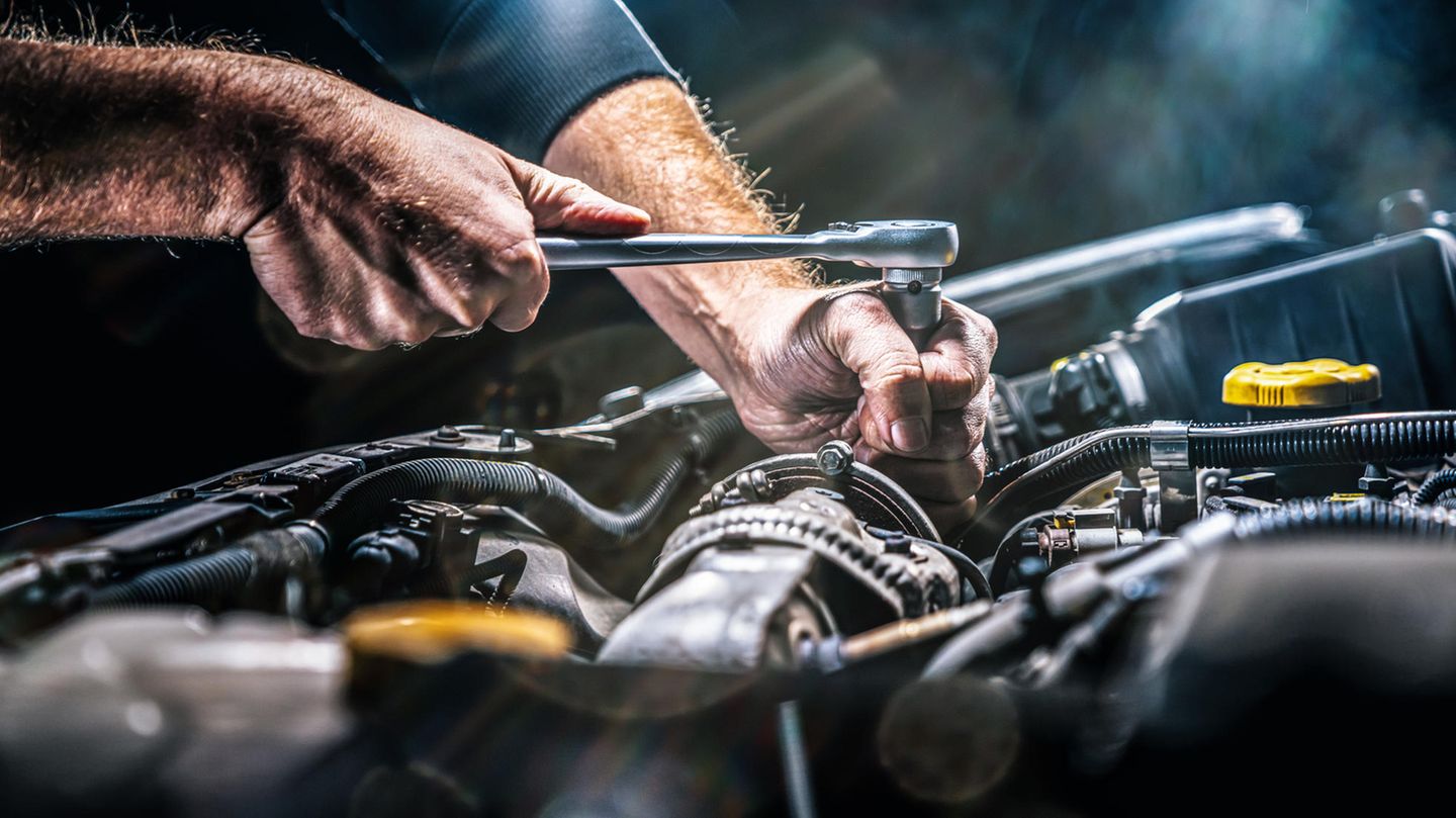 Ein Mechaniker schraubt an einem Automotor