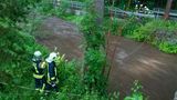 Feuerwehrleute stehen am Fluss