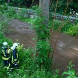 Feuerwehrleute stehen am Fluss