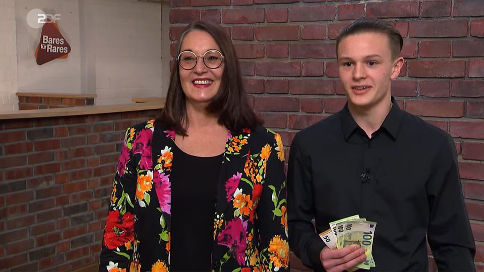 Petra und Moritz Greiner stehen im Studio von Bares für Rares mit einem Bündel Geld in der Hand