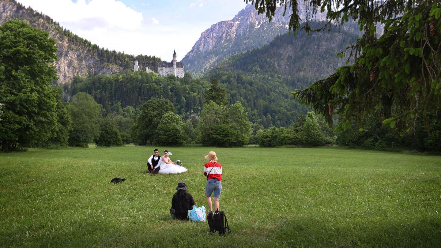 Diesem chinesischen Brautpaar ist die Reise nach Hohenschwangau im Juni diesen Jahres gelungen: Es posiert auf einer Wiese vor dem Schloss Neuschwanstein für Hochzeitsfotos.