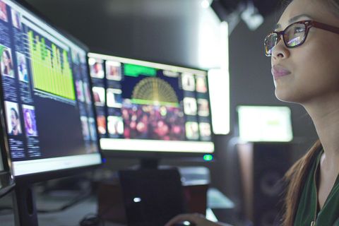 Zwei Monitore anschließen: Eine Frau blickt auf mehrere Monitore.