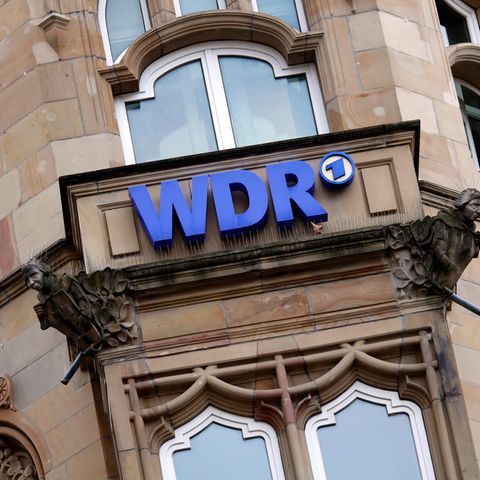 An einer Hausfassade hängt ein blaues Schild mit der Aufschrift WDR