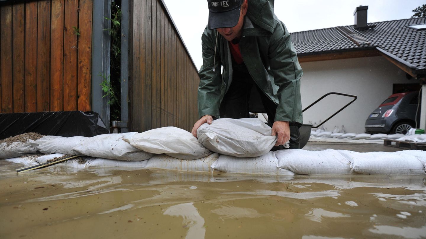 Ein Mann stapelt Sandsäcke bei einem Hochwasser