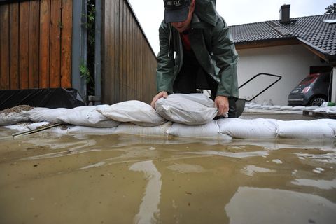 Ein Mann stapelt Sandsäcke bei einem Hochwasser