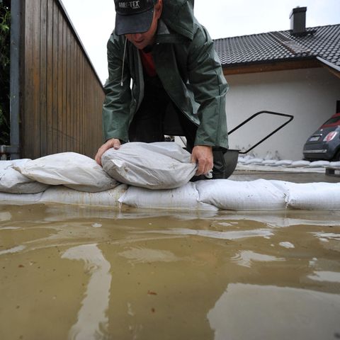 Ein Mann stapelt Sandsäcke bei einem Hochwasser