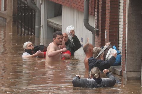 Sechs Menschen stehen teils bis unter die Achseln im Hoochwasser und versuchen, ihre Habseligkeiten trocken zu halten