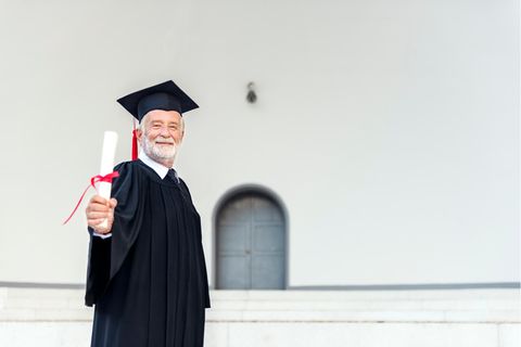 Ein älterer Herr mit seinem Uni-Diplom