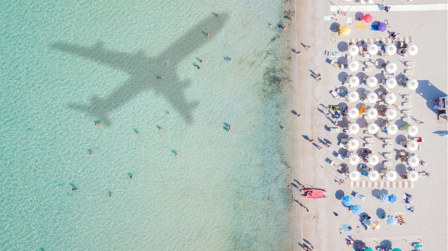 Strandgäste blicken auf eine Flugzeug-Silhouette