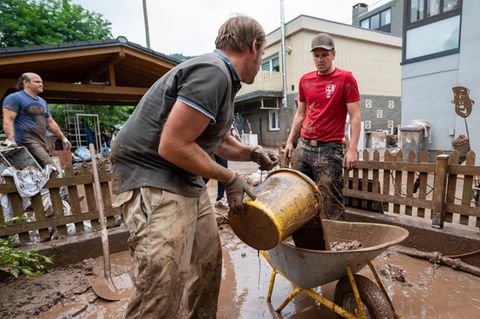 Das große Aufräumen in Kordel: Mit Eimern und Schubkarre entsorgen Anwohner die Schlammmassen nach dem Hochwasser der Kyll in Rheinland-Pfalz