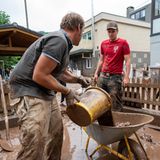 Das große Aufräumen in Kordel: Mit Eimern und Schubkarre entsorgen Anwohner die Schlammmassen nach dem Hochwasser der Kyll in Rheinland-Pfalz