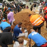In Erftstadt befüllen Dutzende von Helfern diverse Sandsäcke, die benötigt werden, um Dämme zu sichern, die vom Hochwasser aufgeweicht sind.