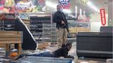 Ein Polizist hält in Johannesburg einen Verdächtigen fest, der ein Geschäft geplündert hat.