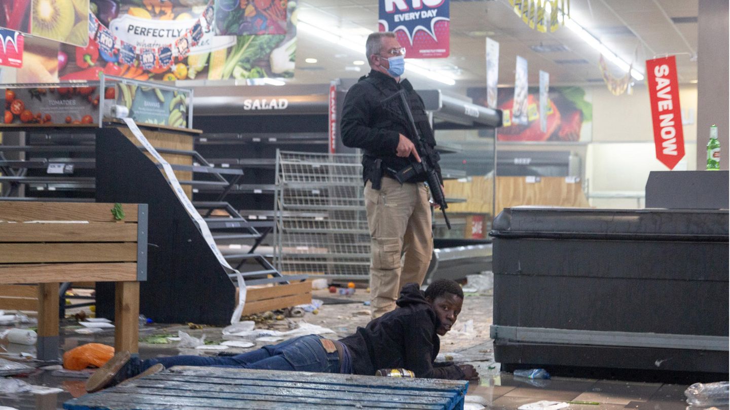Ein Polizist hält in Johannesburg einen Verdächtigen fest, der ein Geschäft geplündert hat.