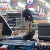 Ein Polizist hält in Johannesburg einen Verdächtigen fest, der ein Geschäft geplündert hat.