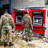 Nichts als Chaos: : Zwei bewaffnete Soldaten stehen nach den Ausschreitungen vor den Geldautomaten einer Bank.