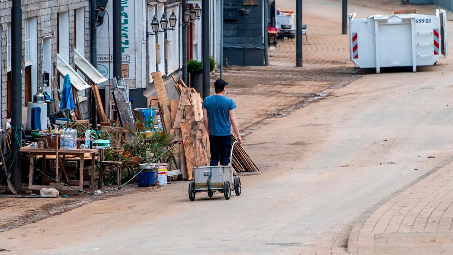 Solingen-Unterburg, Nordrhein-Westfalen: Ein Mann mit einem Handwagen geht an den Schuttbergen vorbei durch die Eschbachstraße
